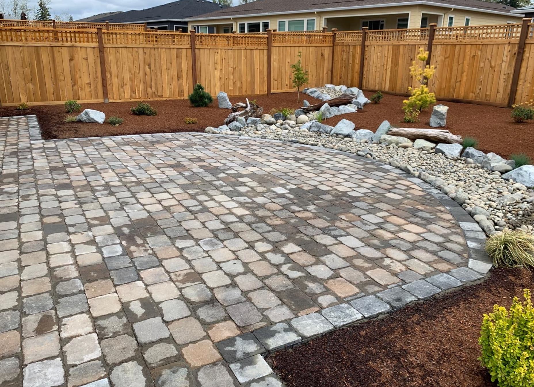 Curved paver patio installation with landscape border in Tacoma WA